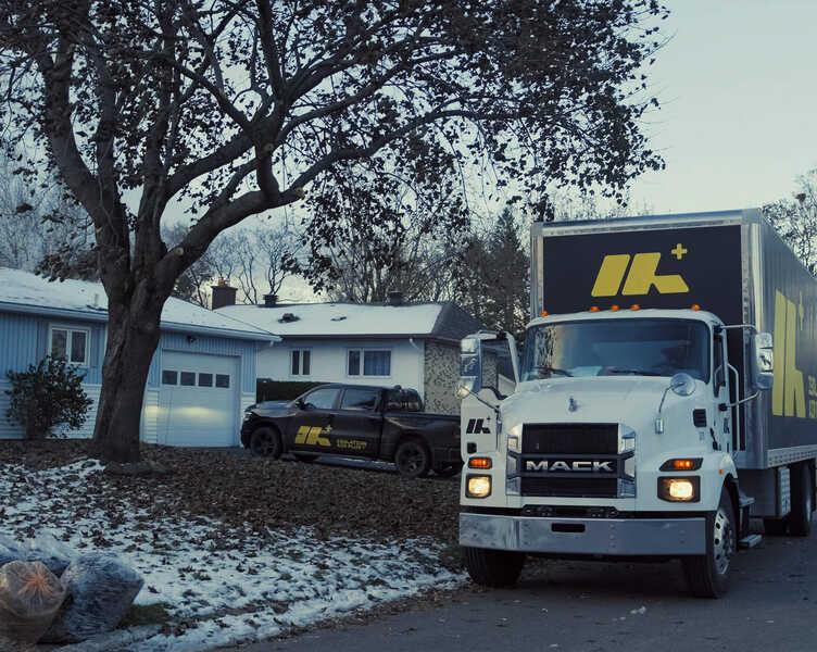 Camions d'Isolation Air-Plus stationnés devant une maison unifamiliale de type bungalow de la région de Québec